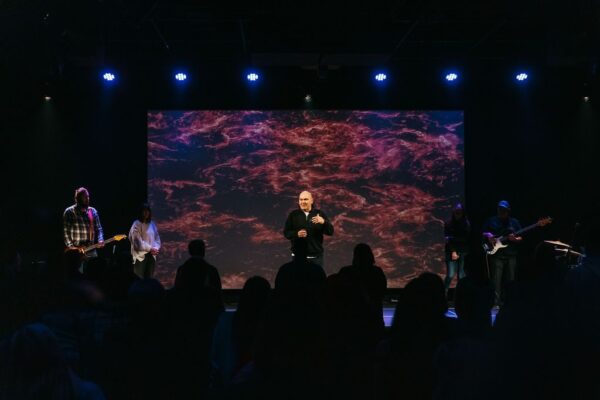 Auditorium stage lighting and 16-foot projection screen during a service at Connexus Church Orillia Campus