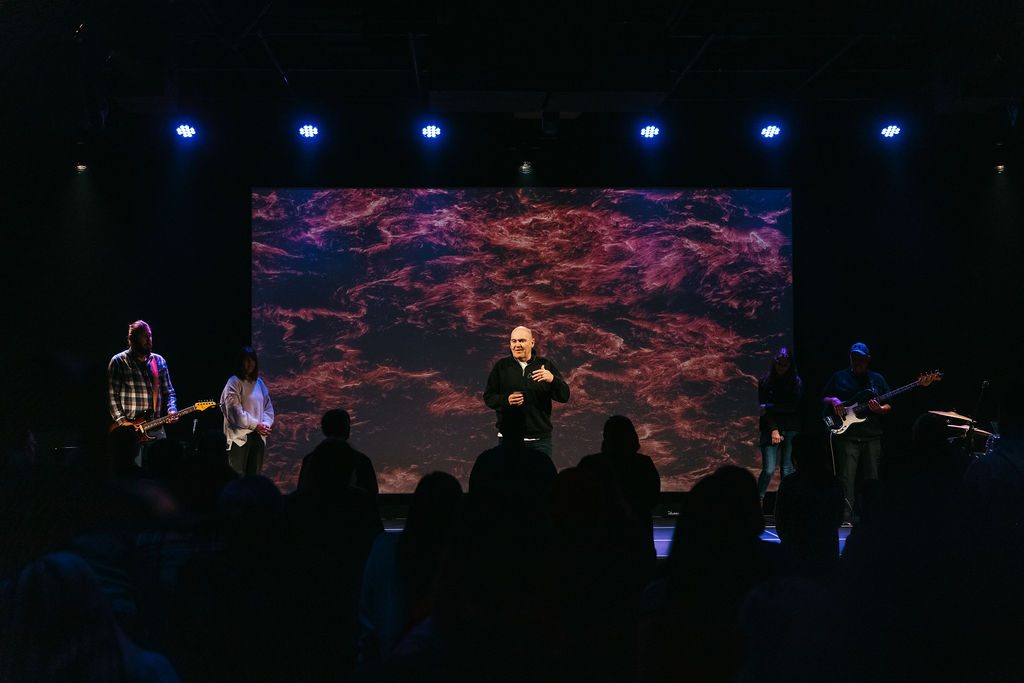 Auditorium stage lighting and 16-foot projection screen during a service at Connexus Church Orillia Campus